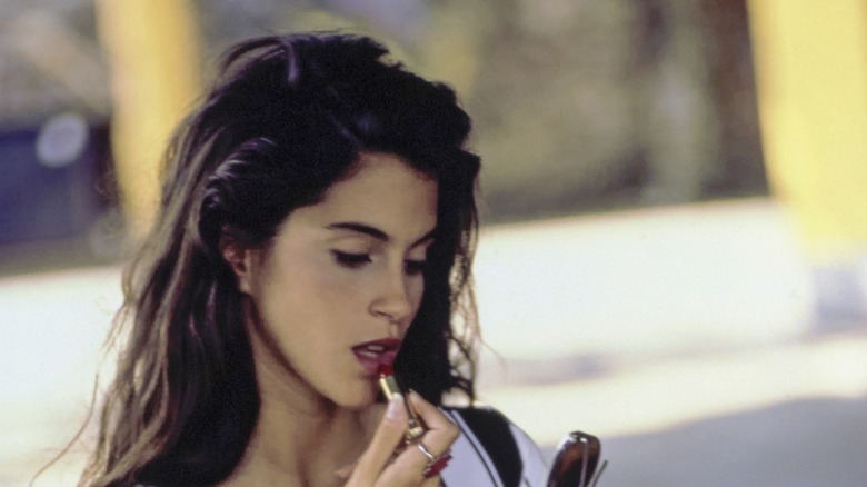 Jami Gertz putting on lipstick