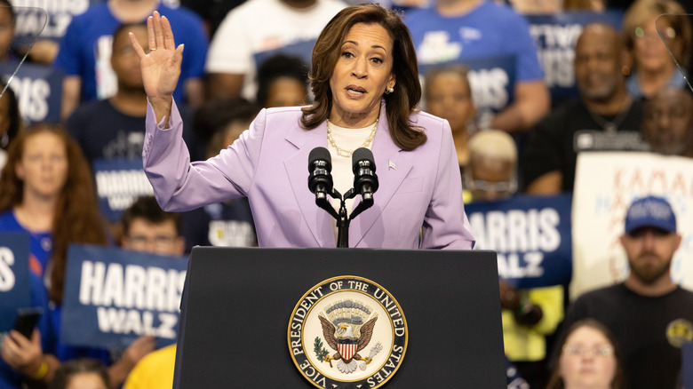 Kamala Harris at podium hand raised in front of crowd