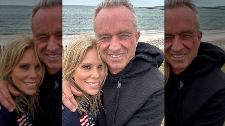 Cheryl Hines and RFK Jr. hugging with ocean background