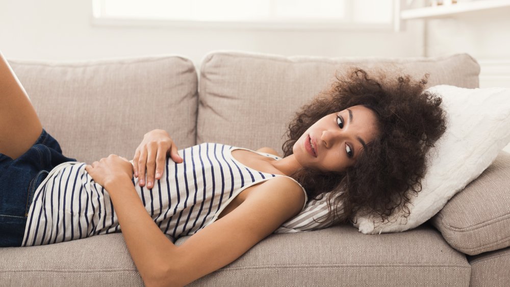 woman laying on the couch with an upset stomach