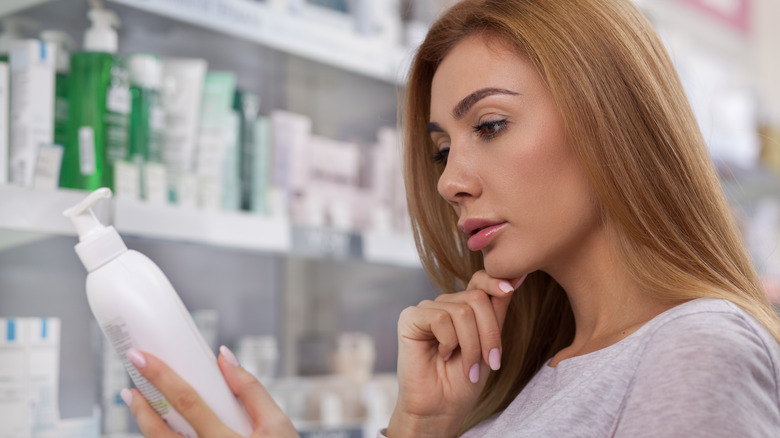 woman looking at shampoo ingredients