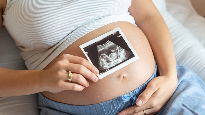 woman holding baby bump, ultrasound