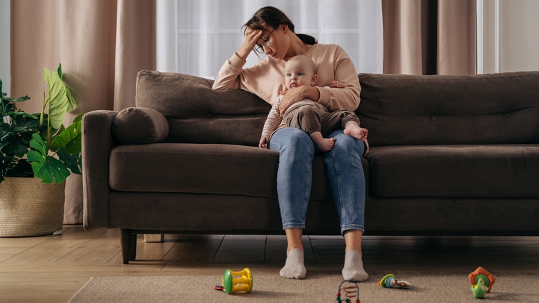 Woman stressed on couch with new baby