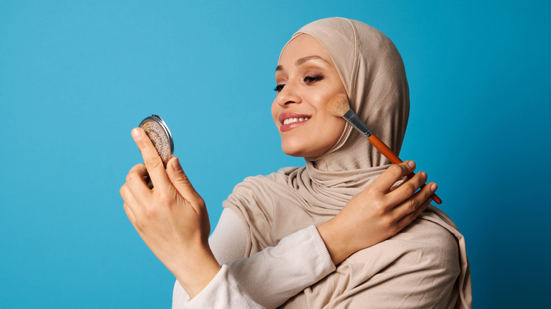 woman putting on bronzer