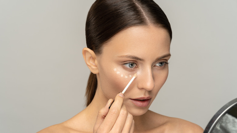 woman putting on concealer