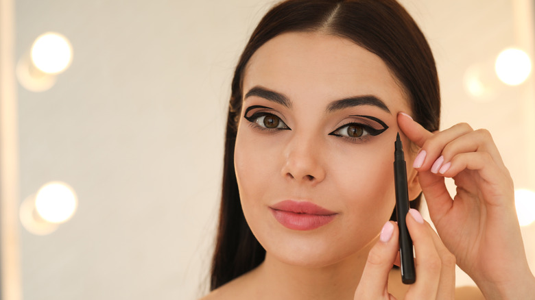 woman putting on eyeliner