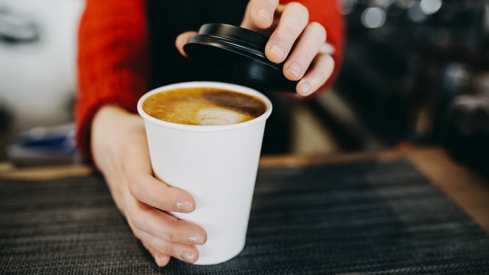 woman holding cup of coffee with flavored syrup