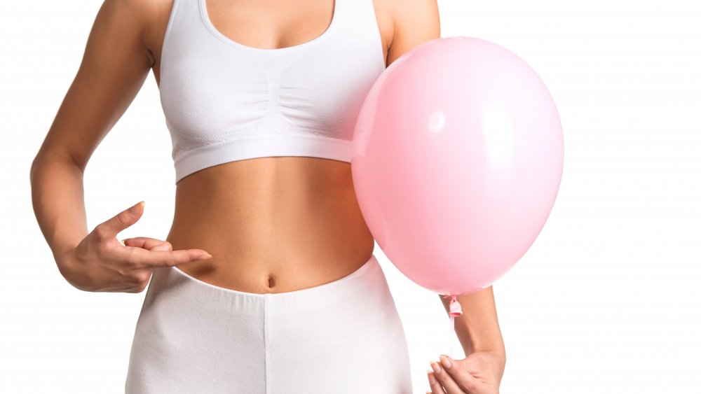 Woman pointing to stomach, holding pink balloon