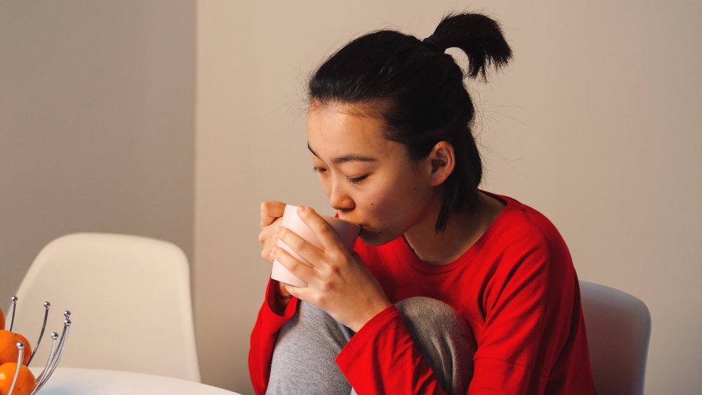 A woman drinking black tea in a red shirt