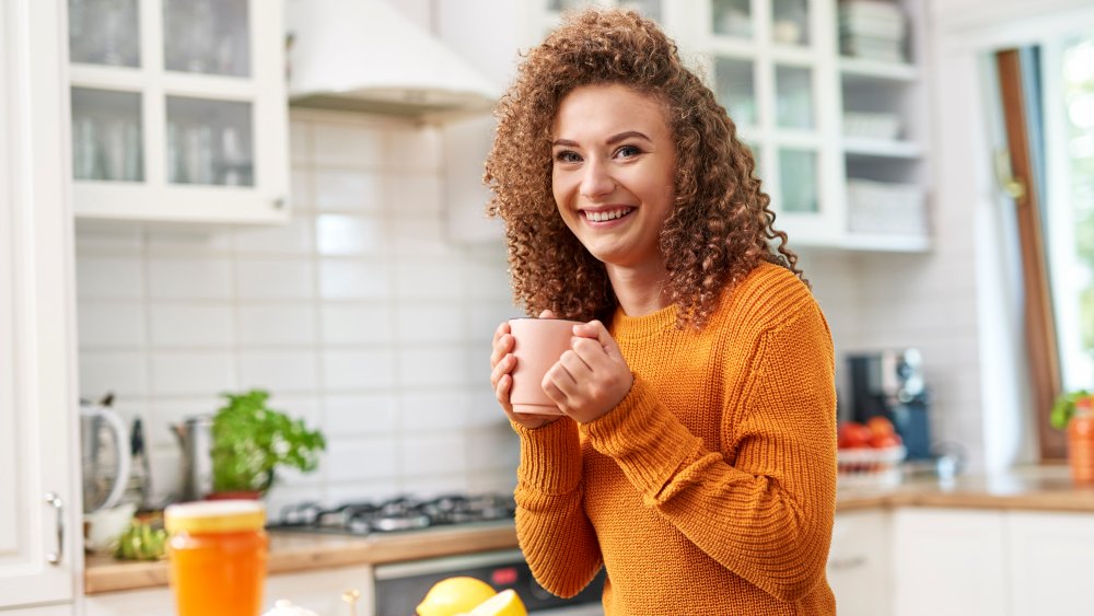 A woman drinking black tea in her kitchen