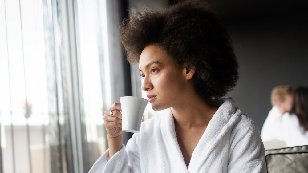 A woman drinking black tea in a bath robe