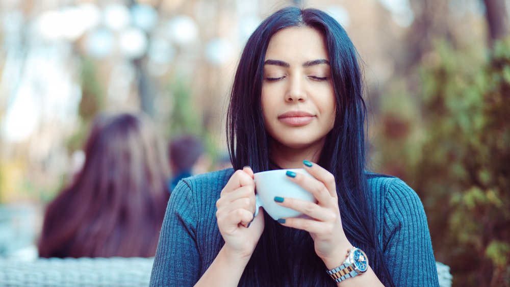 A woman drinking black tea with her eyes closed