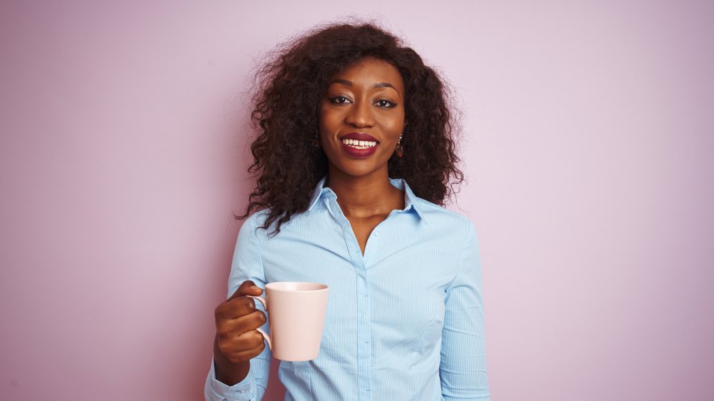 A woman drinking black tea with a purple background