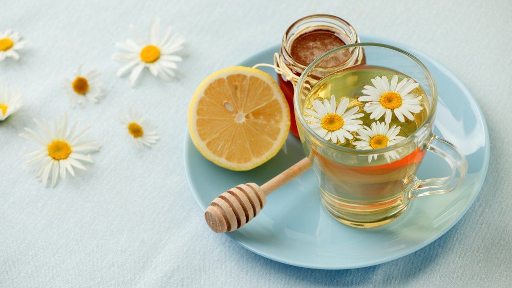Chamomile tea, lemon, honey, and flowers on a plate