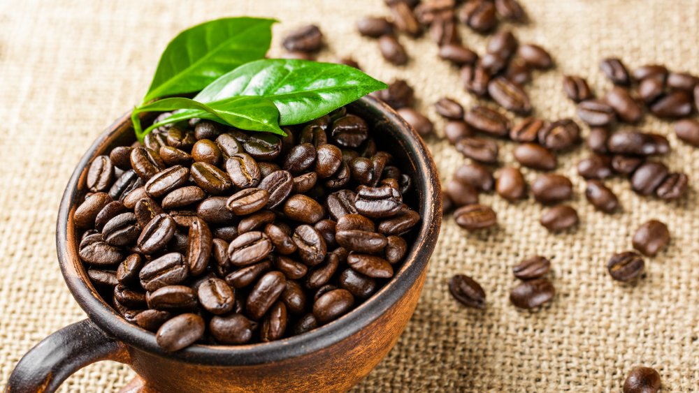 A mug of coffee beans with a leaf