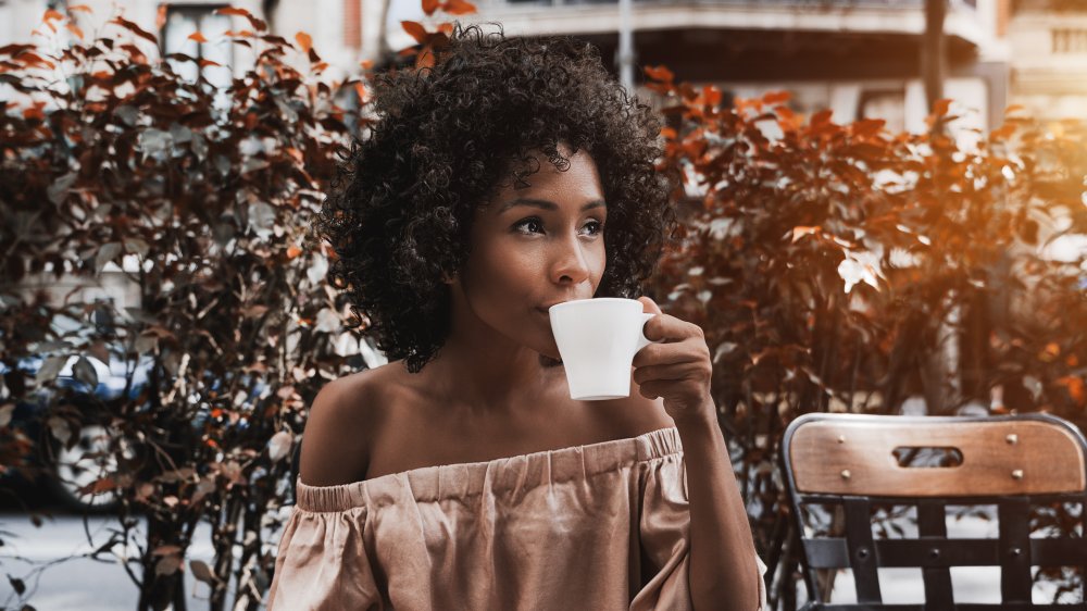 A woman drinking ginger tea at an outdoor cafe