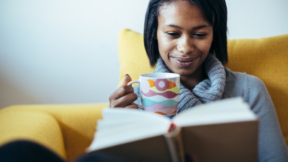 A woman drinking ginger tea while reading a book