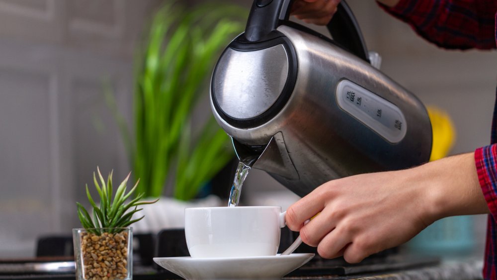 a woman pouring hot water into a mug