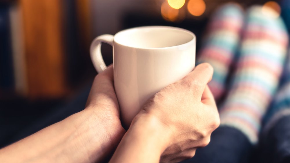 a woman holding a mug of hot water