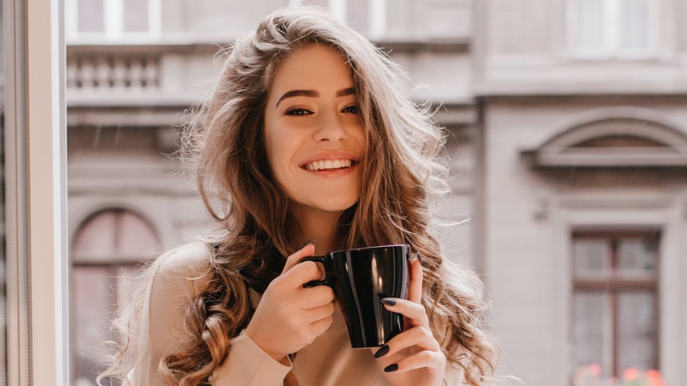 A woman smiling and drinking tea