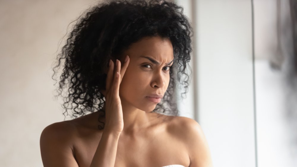 A woman looking at her skin in the mirror