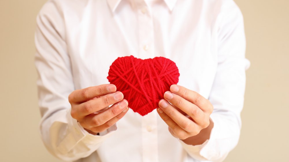 woman holding heart made of yarn