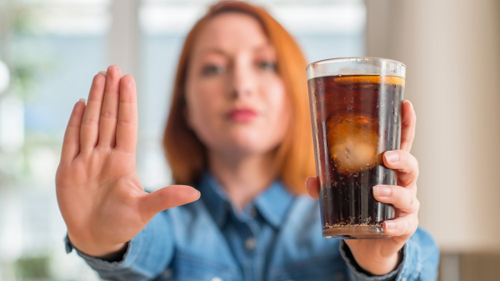 A woman holding a glass of cola, stop drinking soda concept