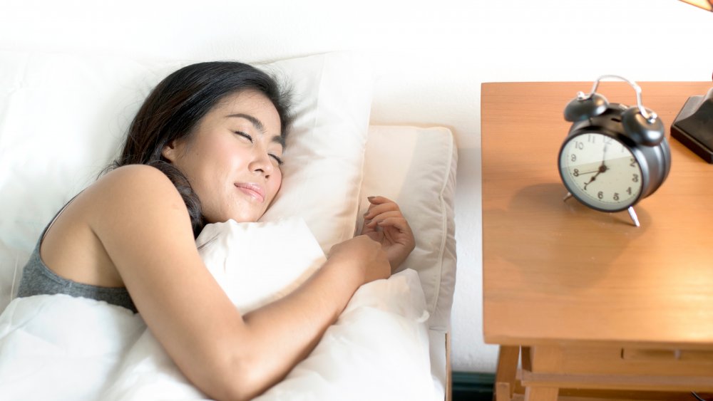 A woman sleeping in bed next to a table