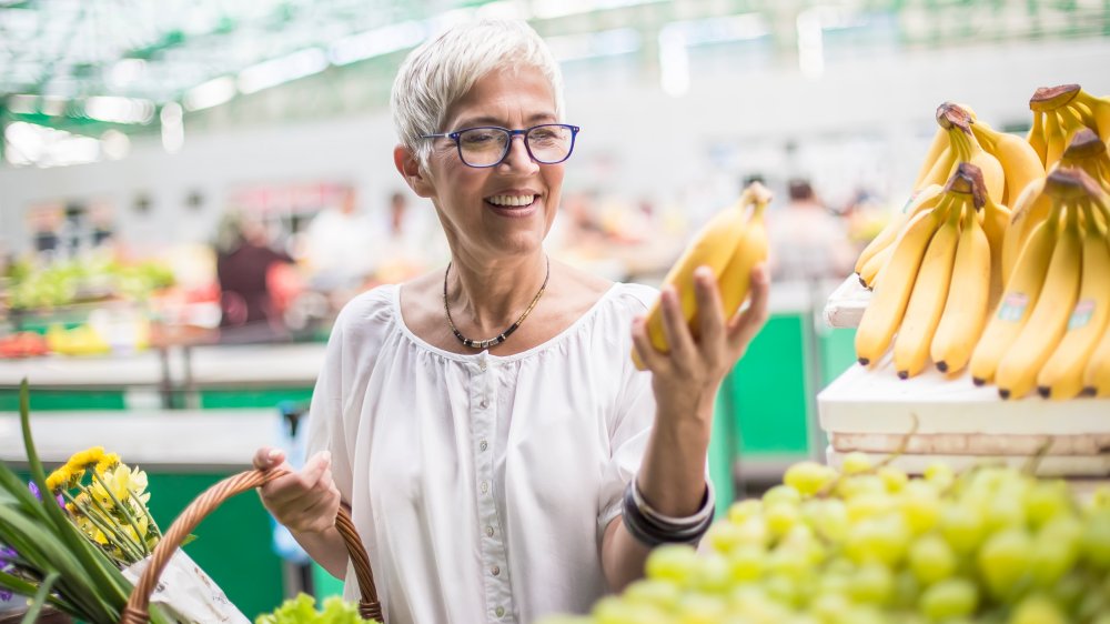 Woman wearing glasses and holding bananas 