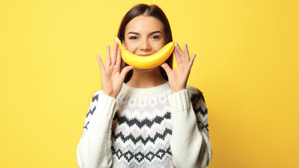 Woman holding banana and smiling 