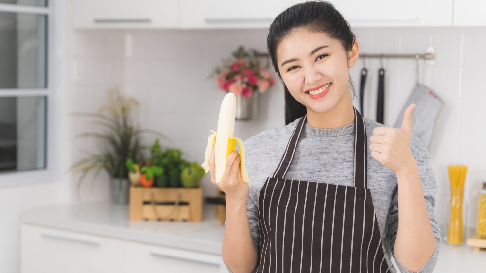 Woman holding banana in kitchen