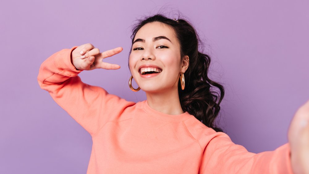 A woman smiling and giving the peace sign