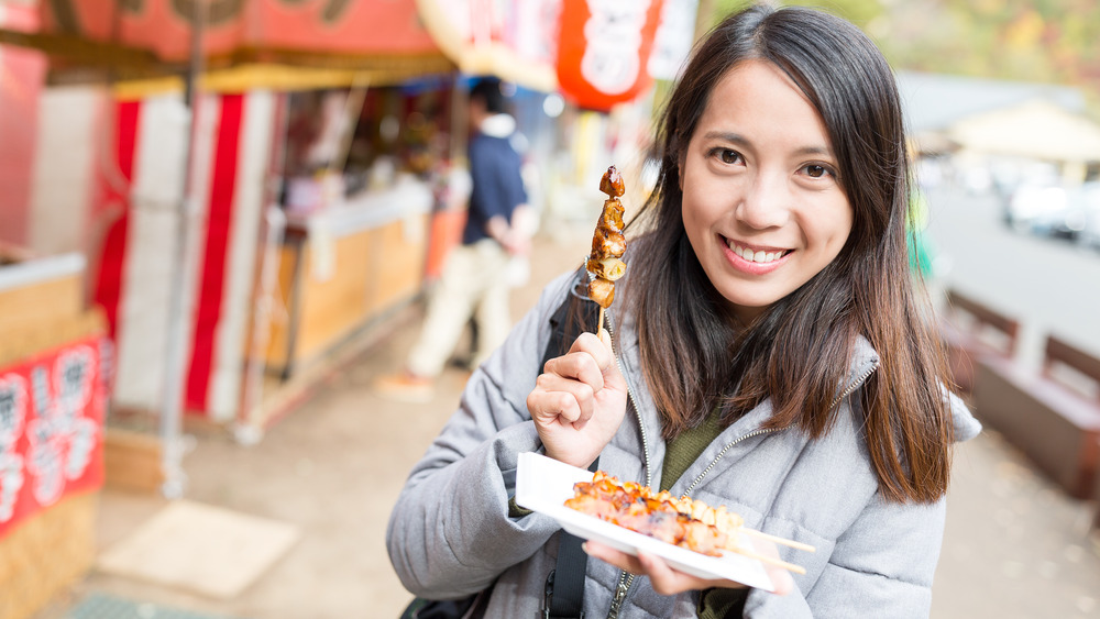 A woman holding chicken skewers