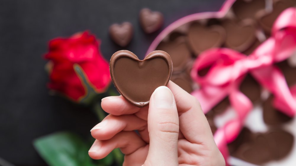 a woman holding a heart-shaped chocolate