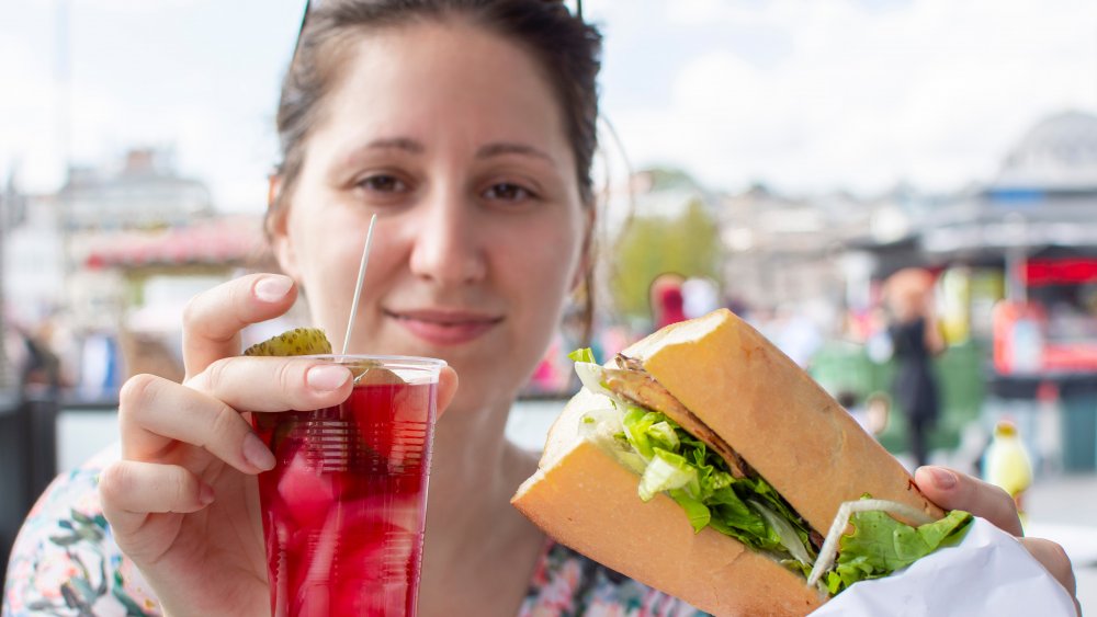 Woman eating deli meat sandwich 