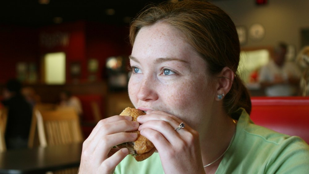 Woman eating deli meat sandwich 