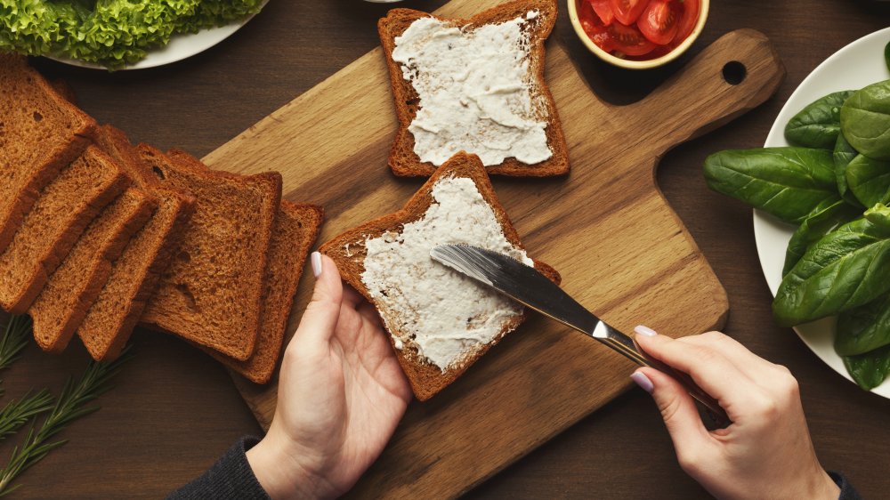 person spreading mayonnaise on bread