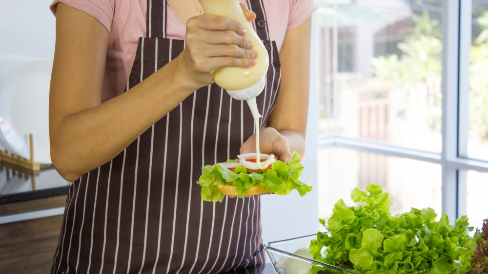 woman putting mayonnaise on food