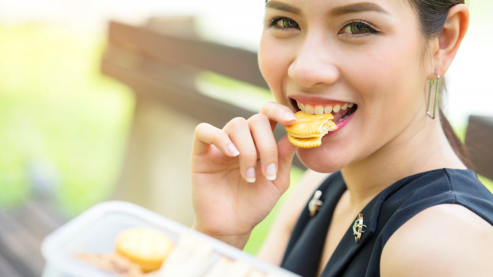 A woman eating a peanut butter cracker