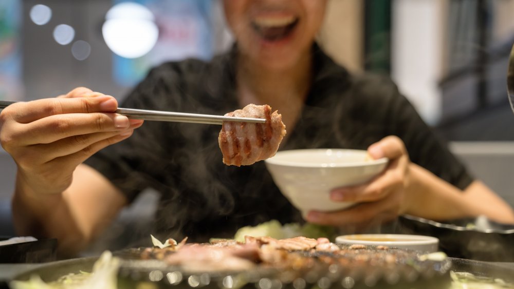 A woman eating pork cutlets at a buffet