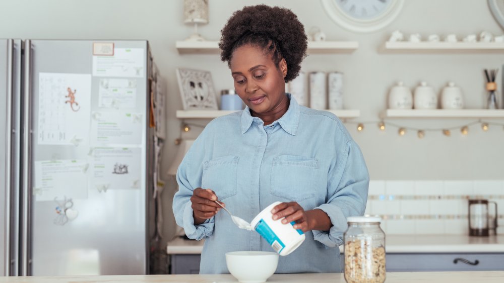 A woman serving herself yogurt in her kitchen