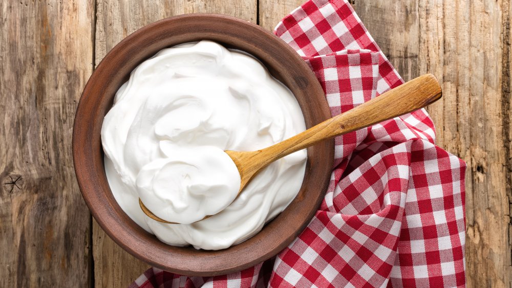 A bowl of yogurt on a table with napkin and spoon