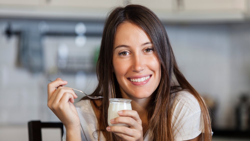 A woman at home eating yogurt