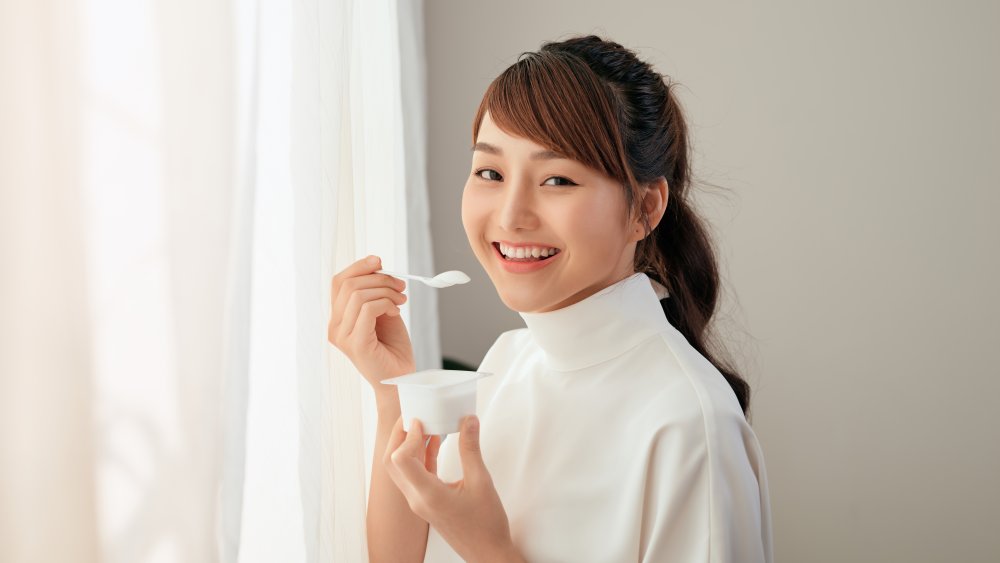 A woman eating yogurt and smiling