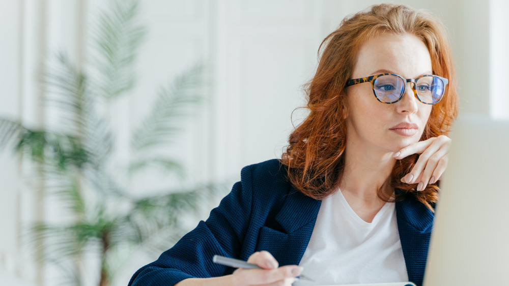 A woman wearing glasses working on her computer