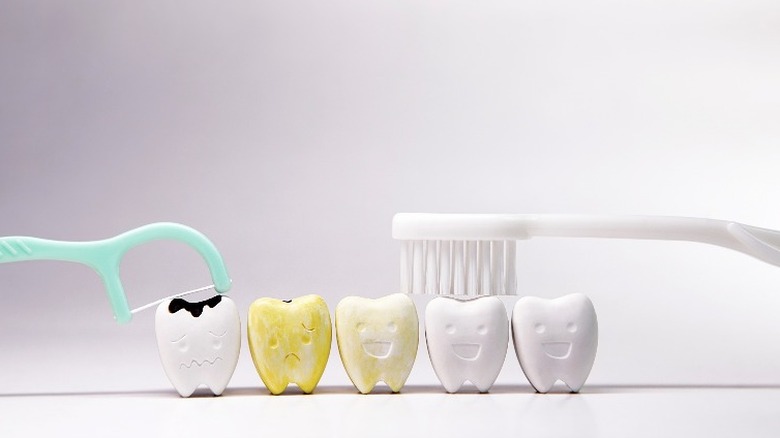 Happy teeth with toothbrush, discolored tooth, and tooth with cavity being flossed