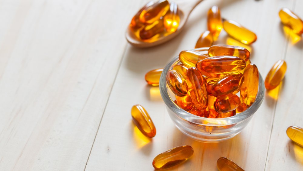 Fish oil supplements in a spoon and a glass bowl