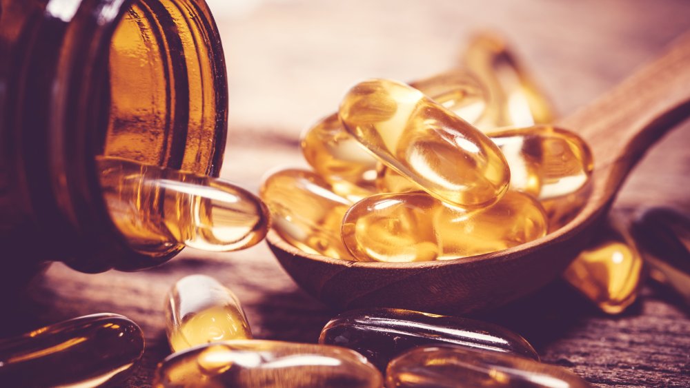 Fish oil supplement spilling onto a table from a jar