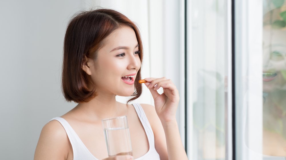 A woman taking a pill with a glass of water