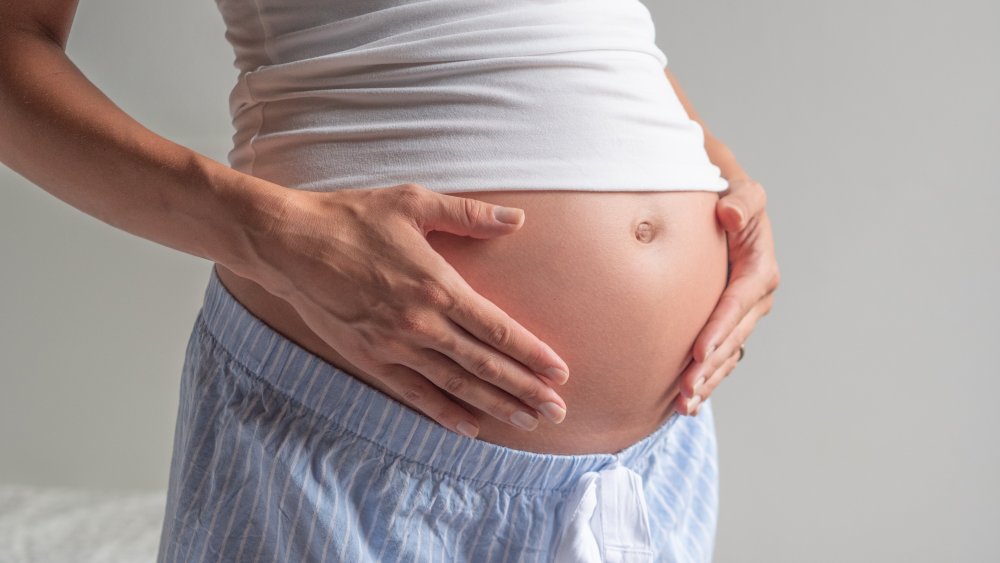 A pregnant woman with her hands on her belly